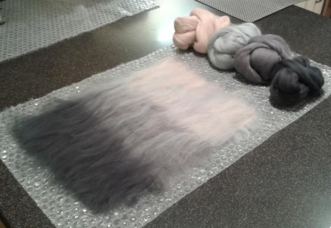 Fibres laid out ready for felting - three shades of grey and a flesh tone to add a little warmth.