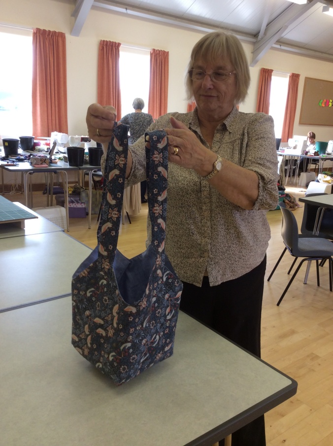 One of the ladies at The Sitting Ducks quilters group showing her handmade blue tote bag.